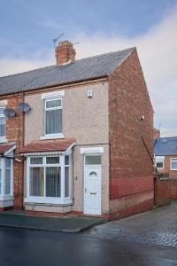 a brick house with a white door on a street at Craigs Nook in Darlington
