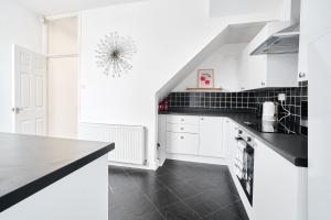 a kitchen with white cabinets and a black counter top at Craigs Nook in Darlington