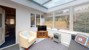 a living room with a chair and a tv and windows at F67 Ischia, Riviere Towans in Hayle