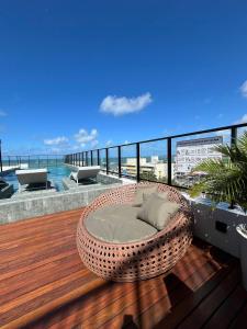 a wicker chair sitting on a deck with the ocean at Get One - João Pessoa in João Pessoa