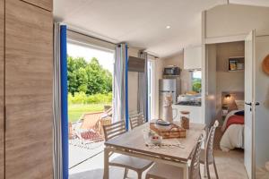 a dining room with a table and chairs and a kitchen at Camping Saint Laurent in Ploemel