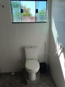 a bathroom with a toilet and a window at Suíte Externa Casal in Rio das Ostras