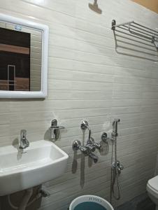 a bathroom with a sink and a mirror and a toilet at Swagat Lodge in Chāngsāri