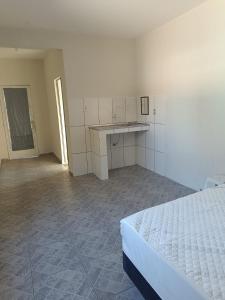 an empty room with a bed and a desk in it at Suíte Externa Casal in Rio das Ostras