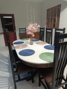 a dining room table with chairs and a vase of flowers on it at Suíte Externa Casal in Rio das Ostras +5 photos
