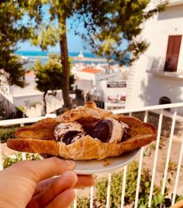 a person holding a plate with a pastry with ice cream at I Cordari B&B in Vieste