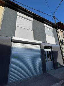 a gray building with a garage door and a window at Apartman Miljanic in Vlasenica