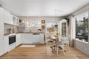 a kitchen with white cabinets and a table with chairs at TV1705-Bindslev-Nordkapvej-4 in Tversted