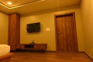 a bedroom with a bed and a television on the wall at Haraa Suites Tiruvannamalai in Tiruvannāmalai +26 photos