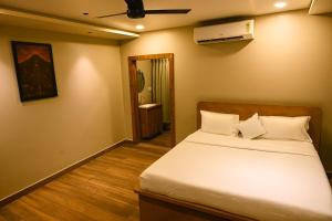 a bedroom with a bed with white sheets and a fan at Haraa Suites Tiruvannamalai in Tiruvannāmalai