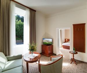 un soggiorno con un divano, un tavolo e una televisione di Grand Hotel Rogaška Premium a Rogaška Slatina