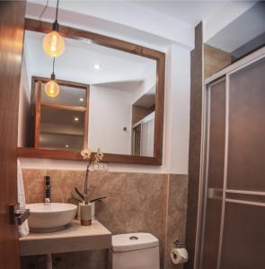 a bathroom with a sink and a toilet and a mirror at Florez de la Villa Apartments & Suites in Cusco +11 photos