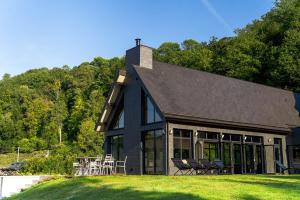 a black house with chairs and tables on a lawn at Les Sources du Val in Saint-Pierre-du-Val
