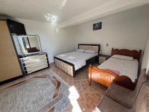 a bedroom with two beds and a dresser and a mirror at Hillside Haven in Durrës