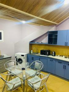 a kitchen with blue cabinets and a glass table and chairs at Tbilisi Vera in Tbilisi City