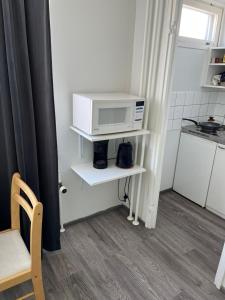 a small kitchen with a microwave on a shelf at Kumpukuja apartment in Kouvola