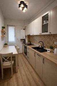 a kitchen with white cabinets and a table and a sink at Cozy space in Iaşi