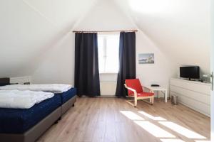 a bedroom with a bed and a red chair at Villa Seaview met Sauna in Makkum