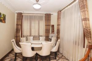 a dining room with a white table and chairs at Cosmil Executive Suites Najjanankumbi Kampala in Kampala