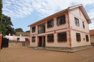 坎帕拉的住宿－Cosmil Executive Suites Najjanankumbi Kampala，粉红色的建筑,街道上设有黑窗