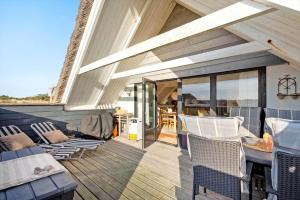 a patio with a table and chairs on a deck at 2289-Ringkobing-Nordso-Ferievej-21 in Klegod