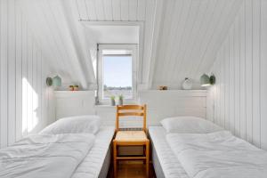 two beds in a room with a chair and a window at 2289-Ringkobing-Nordso-Ferievej-21 in Klegod