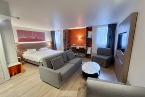 a hotel room with a bed and a living room at Best Western Hotelio Montpellier Sud in Montpellier