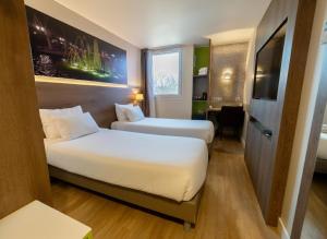 a hotel room with two beds and a desk at Best Western Hotelio Montpellier Sud in Montpellier