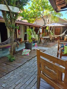 a wooden deck with a bench and tables and chairs at Pousada Casa Rosa in Itacaré