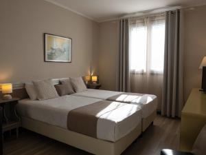 a bedroom with a large bed and a window at Hotel Les Oliviers in Fayence