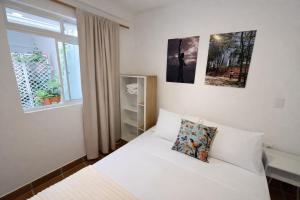 a bedroom with a white bed and a window at Casa Mompa in Bucaramanga