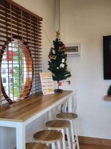 a christmas tree sitting next to a table with stools at 19 House in Ban Khlong Pleo +15 photos