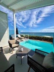 a patio with a swimming pool with chairs and a table at Villa Ar Mor - Oceanfront pool & Saint-Barth view Oyster pond in Saint Martin