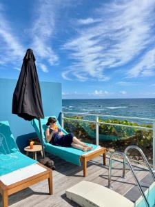 a woman sitting on a couch on a deck overlooking the ocean at Villa Ar Mor - Oceanfront pool & Saint-Barth view Oyster pond in Saint Martin