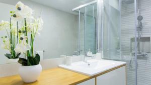 a bathroom with a white sink and a vase of flowers at Praça 44 in Braga +55 photos