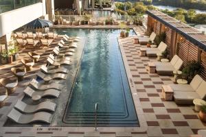 a pool with chaise lounge chairs and tables on a building at ROOST Rainey in Austin