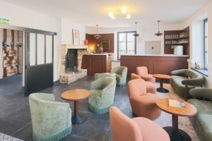 a lobby with chairs and tables and a fireplace at Logis Hostellerie la Chaumière in Arsonval