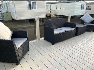 two wicker chairs sitting on a deck next to a house at Caravan by the beach in Kinmel Bay