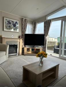 a living room with a television and a fireplace at Caravan by the beach in Kinmel Bay