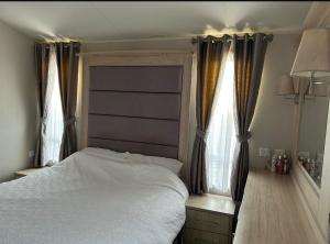 a bedroom with a white bed and two windows at Caravan by the beach in Kinmel Bay