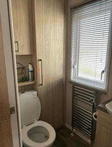a small bathroom with a toilet and a window at Caravan by the beach in Kinmel Bay +5 photos