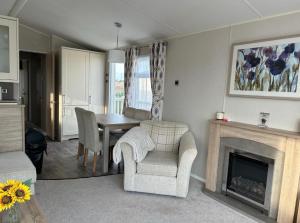 a living room with a table and chairs and a fireplace at Caravan by the beach in Kinmel Bay