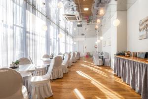 a dining room with white tables and white chairs at Hotel Tammsaare Full Automated Hotel in Pärnu