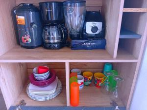 a wooden shelf with cups and plates and a blender at Casa de Milo in Ahuachapán