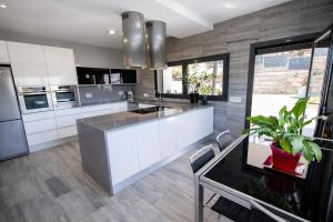 a kitchen with white cabinets and a sink and a table at Catalunya Casas Modern Marvel,15 min to Costa Brava beaches! in Sils