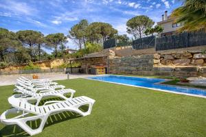 a row of white lounge chairs next to a swimming pool at Catalunya Casas Modern Marvel,15 min to Costa Brava beaches! in Sils