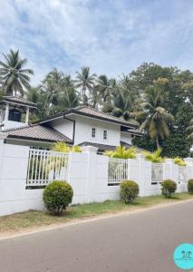 a white fence in front of a house at Nuwan Home Vacation Villa in Wennappuwa