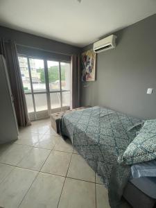 a bedroom with a bed and a window at Casa em itapema fácil acesso e bem localizada in Itapema