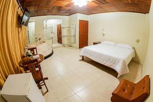 a bedroom with a bed and a bathroom with a tub at Hotel Oro Verde Iquitos in Iquitos