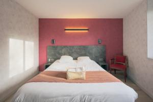 a bedroom with a large bed with a red wall at Logis Hostellerie la Chaumière in Arsonval